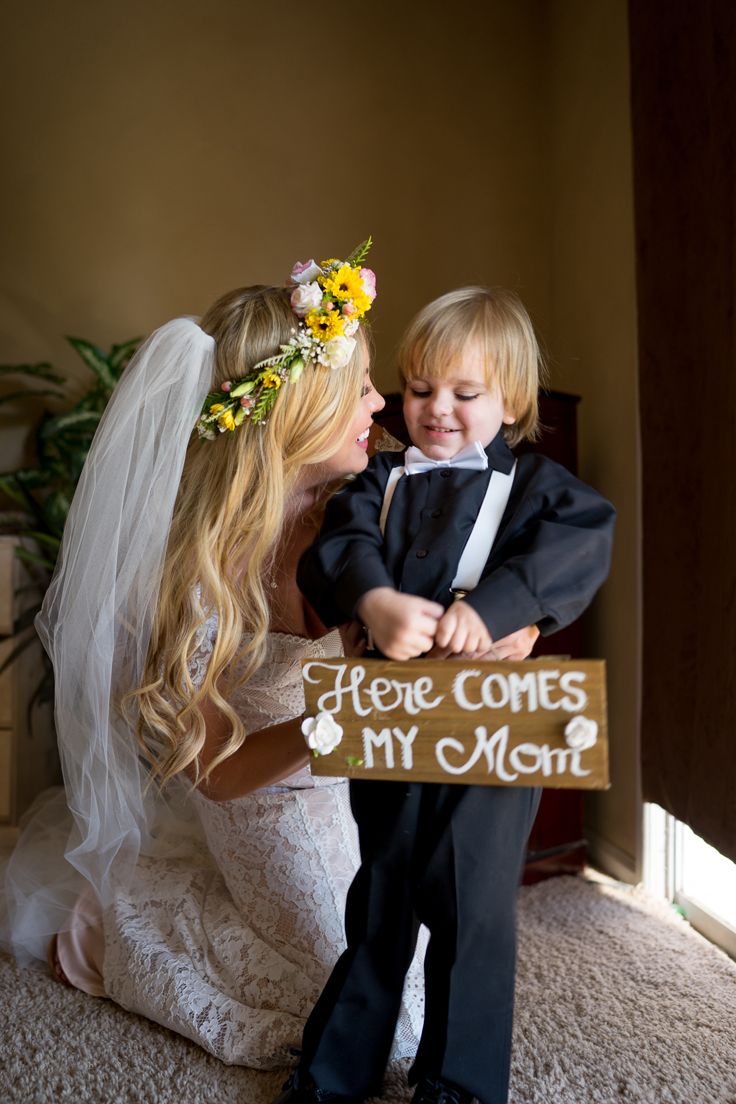 a young boy and woman holding a sign that says here comes my mom