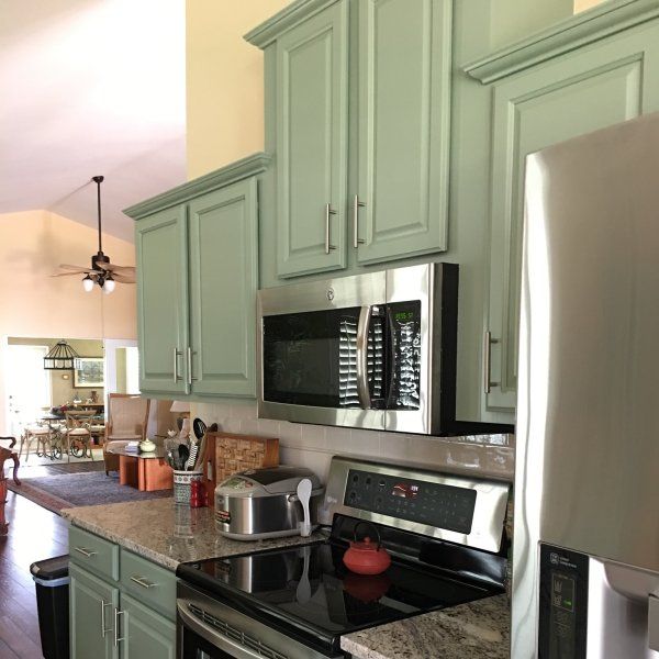 a kitchen with green cabinets and stainless steel appliances