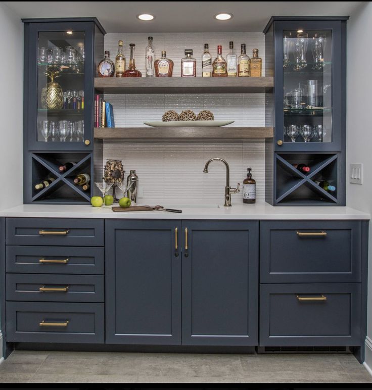 a kitchen with blue cabinets and shelves filled with liquor bottles on top of counter tops