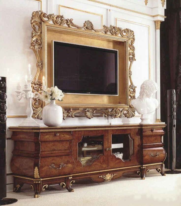 an ornate wooden entertainment center with a large mirror on the wall and vases in front of it