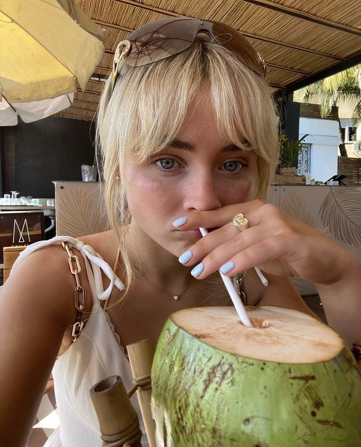 a woman sitting in front of a coconut drink