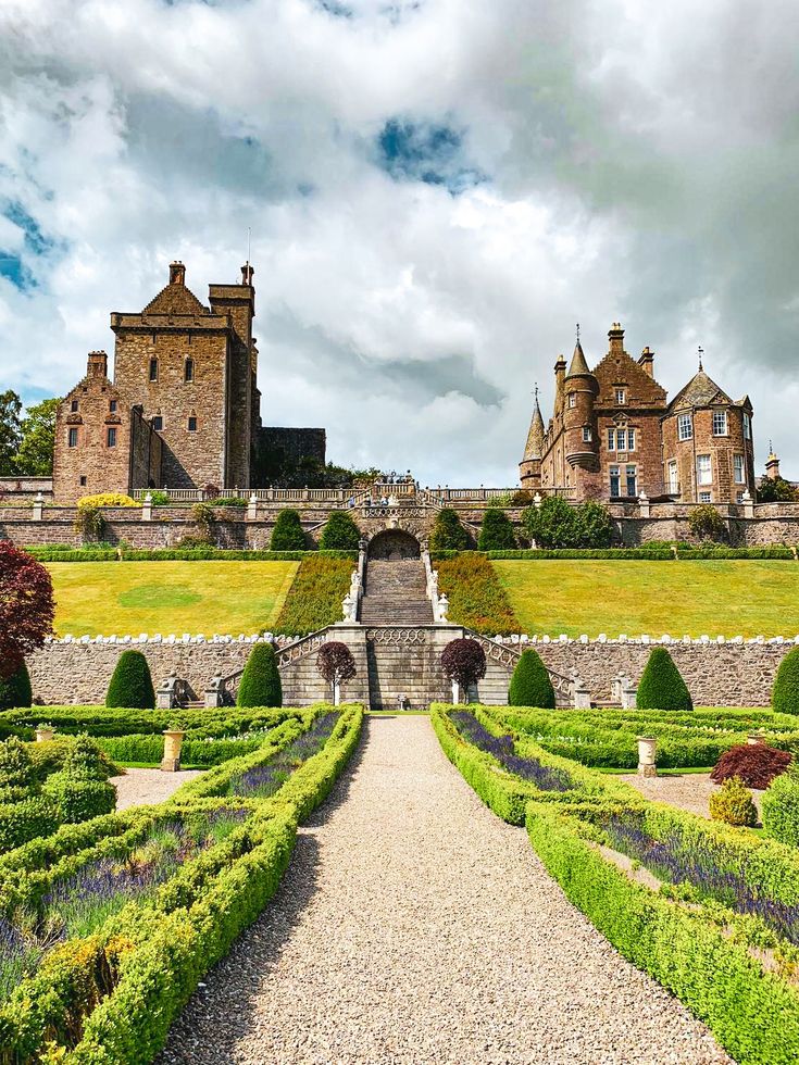 a large building with many hedges in front of it and a walkway leading to the entrance