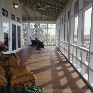 an empty porch with wicker chairs and large windows