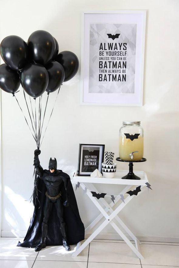 the batman balloon is being held up in front of a table with pictures on it