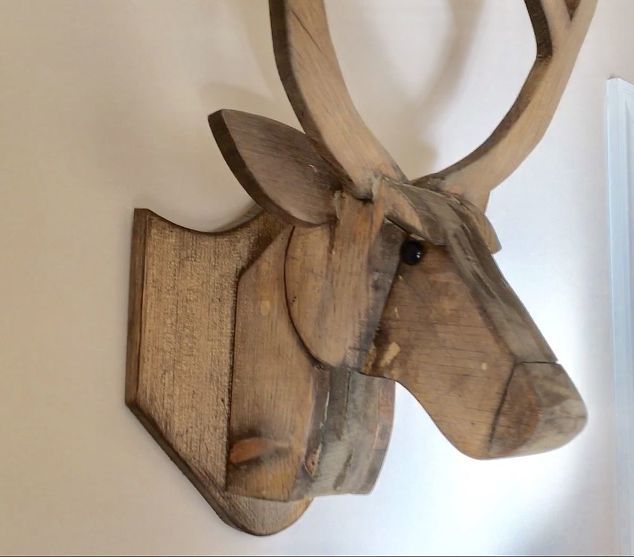 a wooden deer head mounted to the side of a wall