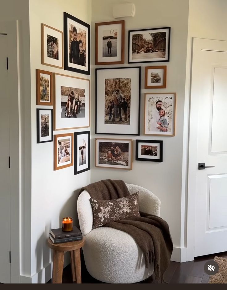 a living room with pictures on the wall and a white chair in front of it