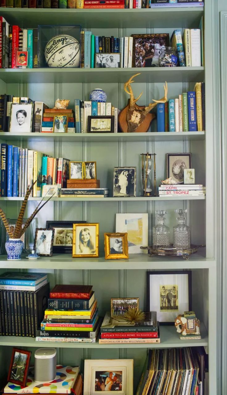 a bookshelf filled with lots of books next to a wall covered in pictures