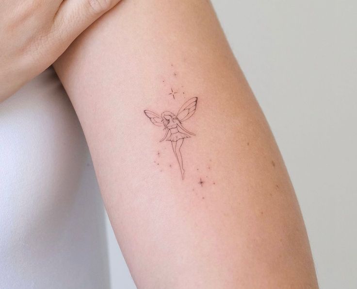 a woman's arm with a small tattoo of a fairy on the back of it