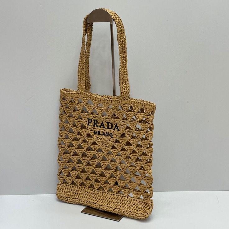 Embrace effortless summer style with this woven raffia tote bag, inspired by the iconic Prada design. Its open-weave construction and natural tan hue evoke a sense of carefree elegance, perfect for sunny days and beachside adventures. The spacious interior provides ample room for your essentials, while the "PRADA MILANO" inspired logo adds a touch of high-fashion appeal. Woven Raffia, Open Weave, Loafer Sneakers, Natural Tan, Sneaker Boots, Sunny Days, Casual Shoes, Prada, Weaving