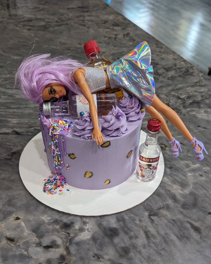 a barbie doll laying on top of a purple cake covered in sprinkles