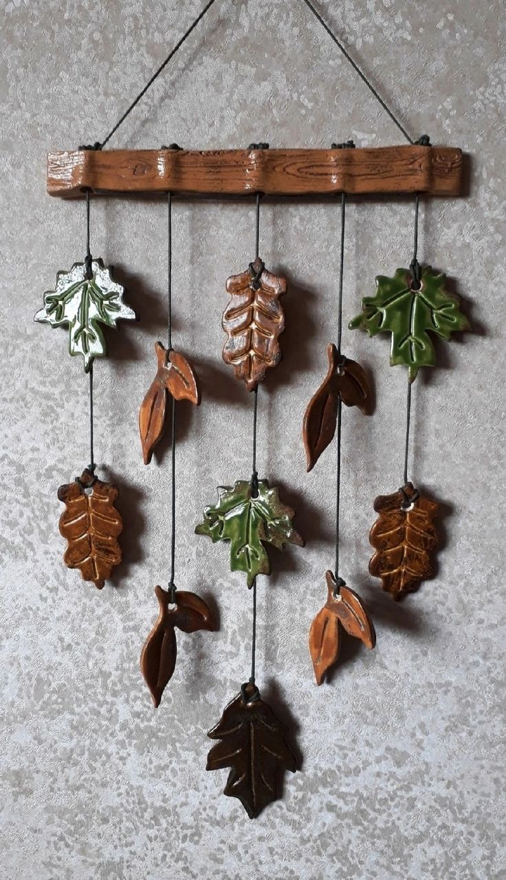 a wooden wind chime with leaves hanging from it's sides on a wall