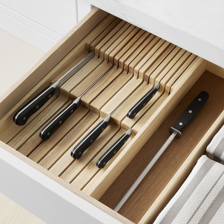 an open drawer with knives and spoons in it