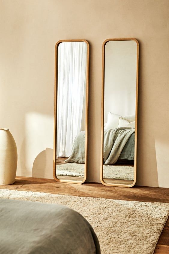 three mirrors on the wall near a bed