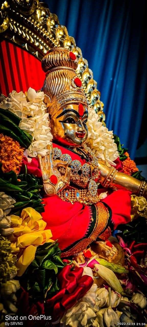 an idol is sitting on the ground with flowers in front of it and a blue curtain behind it