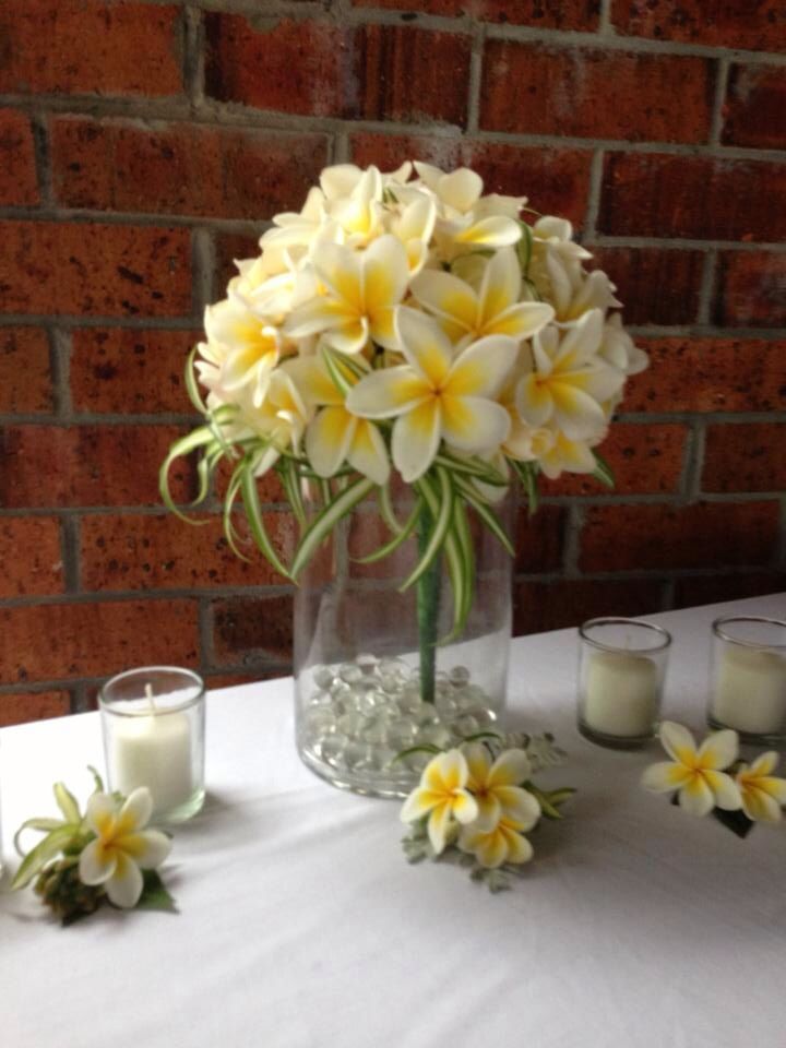 a vase filled with yellow flowers sitting on top of a table next to some candles