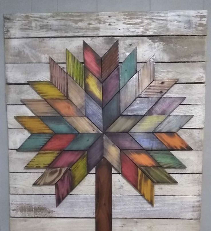 a wooden wall hanging with a multicolored wood tree on it's side