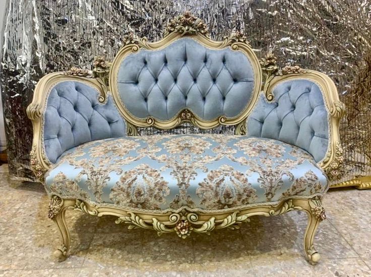 an antique couch with blue upholstered fabric and gold trimmings on it