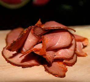 sliced ham sitting on top of a wooden cutting board