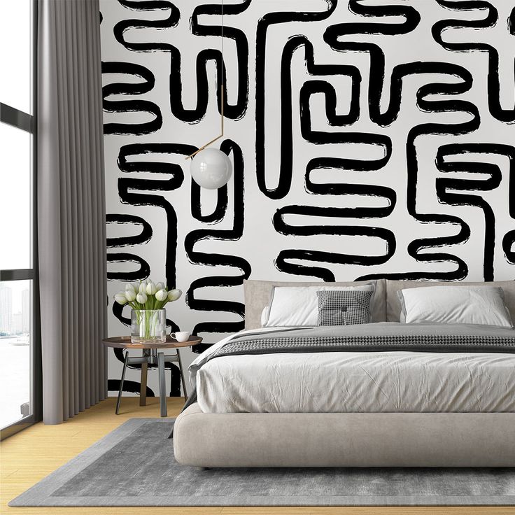 a large bed sitting in front of a wall with black and white designs on it