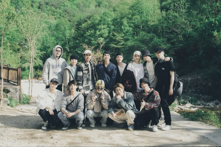 a group of young men standing next to each other on a dirt road in front of trees