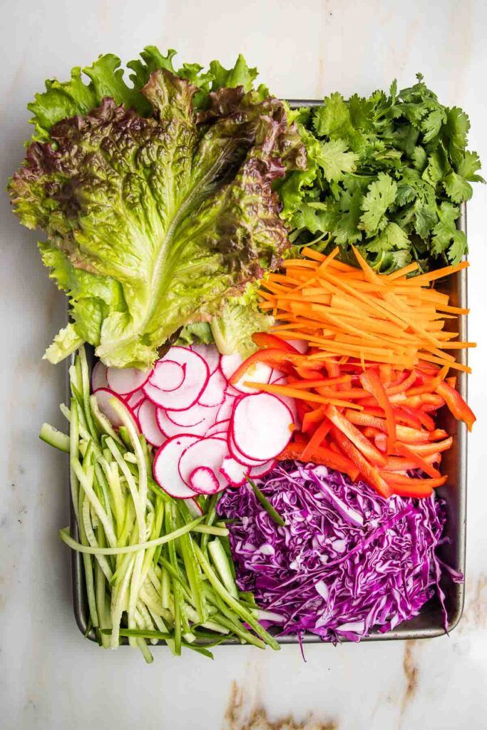 a tray filled with different types of veggies on top of a marble counter