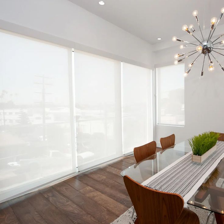 a dining room table and chairs in front of large windows