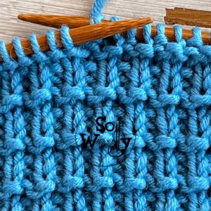 the crochet stitch is being worked on with two knitting needles and one wooden needle