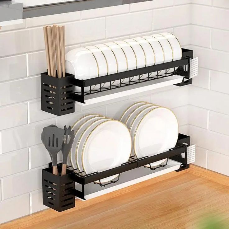 two black racks holding plates and utensils on a kitchen counter with white tiles