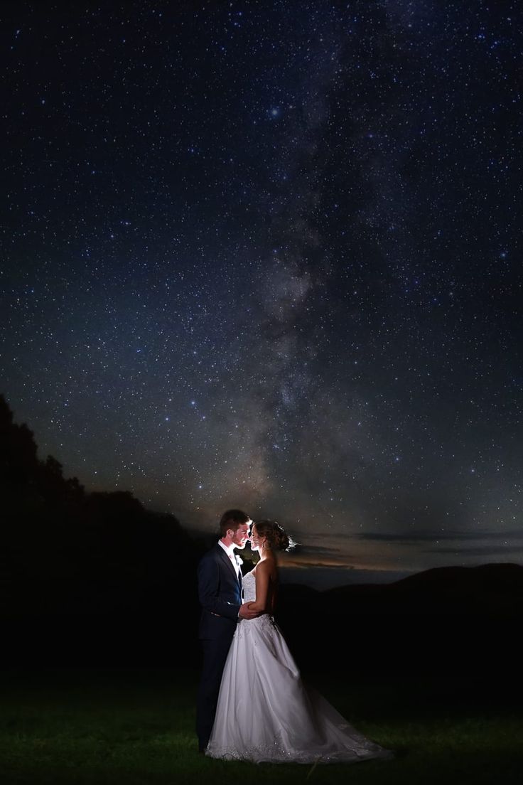 a bride and groom kissing under the night sky