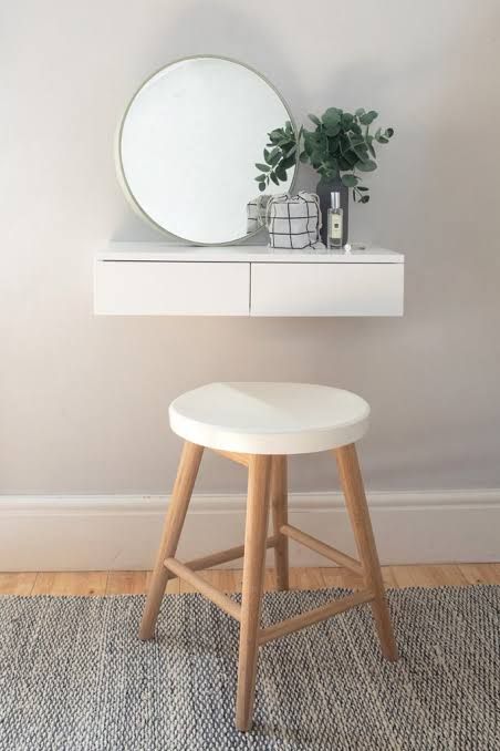 a white stool sitting under a mirror on top of a wooden table next to a potted plant