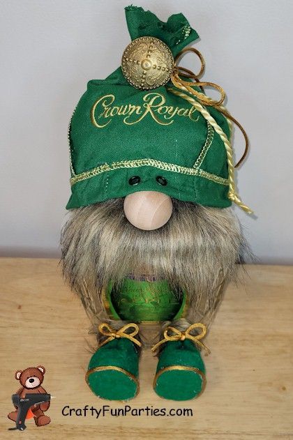 a green and gold hat with a long beard on top of a wooden table next to a pair of shoes