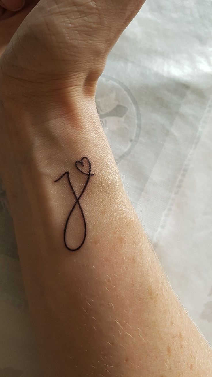 a person with a tattoo on their wrist holding up the letter j to symbolize love