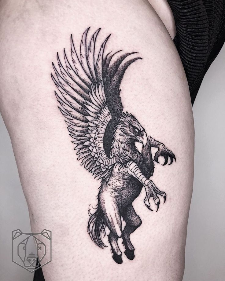 a woman's thigh with an eagle and demon tattoo design on the side of her leg