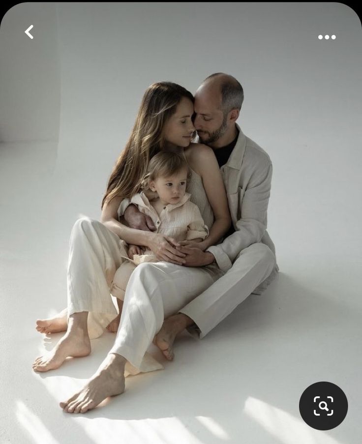 a man, woman and child are sitting on the floor with their arms around each other