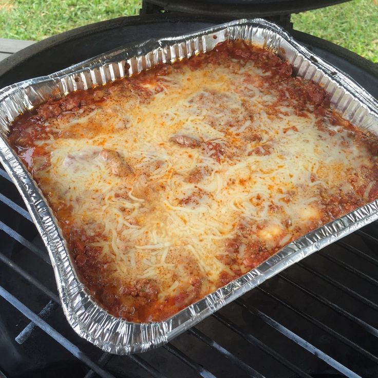 a pizza sitting on top of a grill covered in cheese