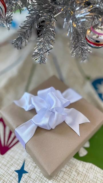 a wrapped present under a christmas tree with ornaments