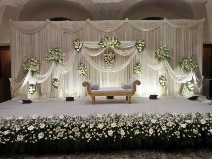 the stage is decorated with white flowers and greenery for an elegant wedding or special event