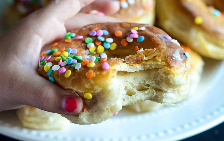 a hand holding a half eaten doughnut with sprinkles on it's side