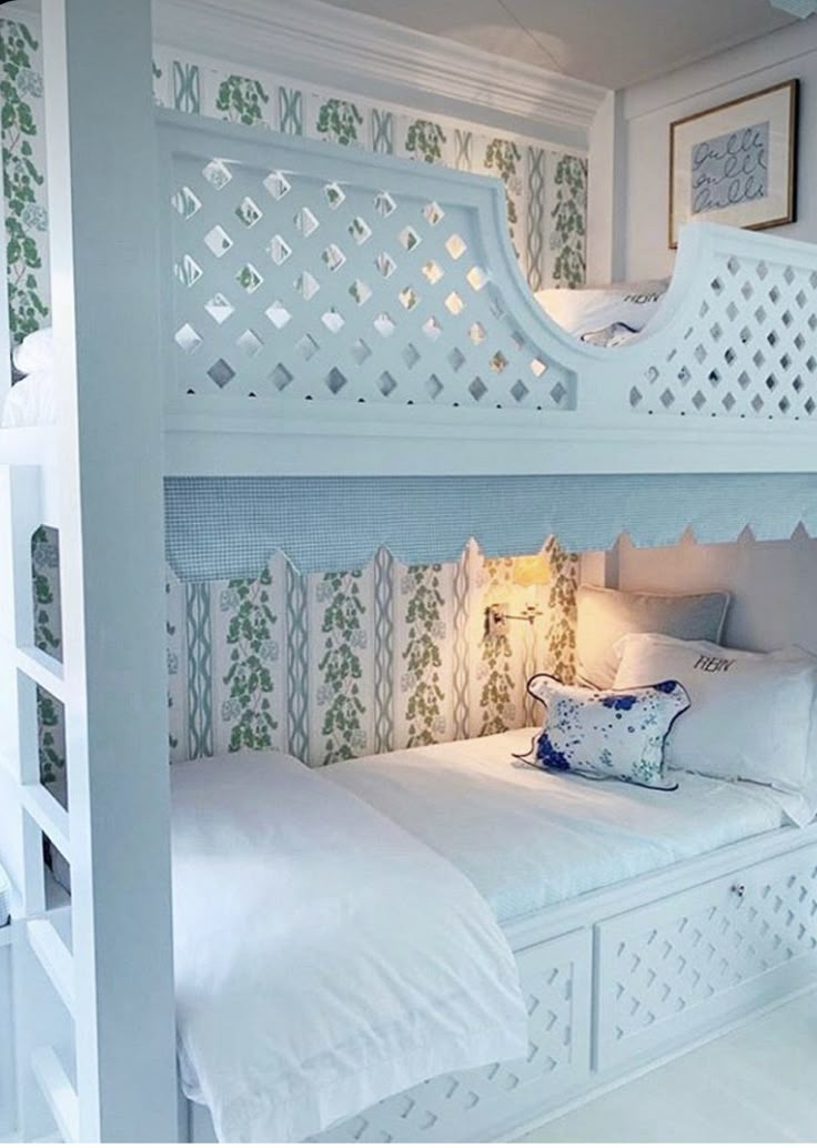 a white bunk bed sitting in a bedroom next to a wall mounted mirror and lamp