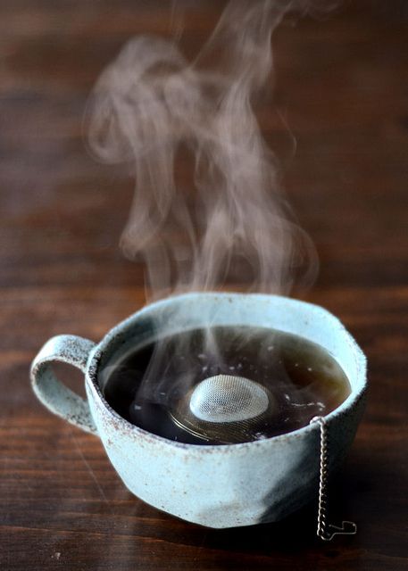 steam rising from a tea cup on a wooden table