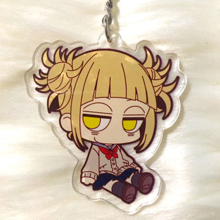 an anime character keychain with yellow eyes and blonde hair sitting on a white surface