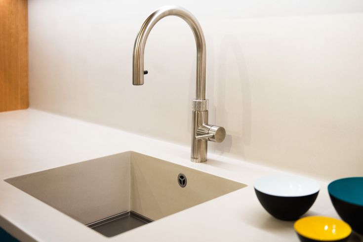 a kitchen sink sitting under a faucet next to two bowls on the counter