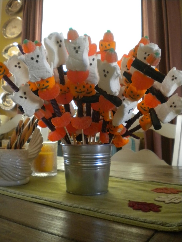 a vase filled with candy and marshmallows on top of a wooden table