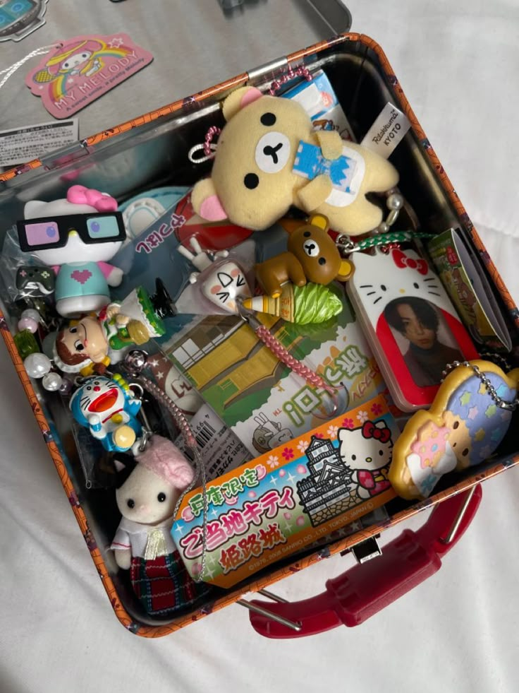 a suitcase filled with lots of toys and other items on top of a white sheet