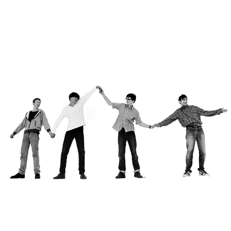 four young men are holding hands and standing in the same direction with their arms stretched out