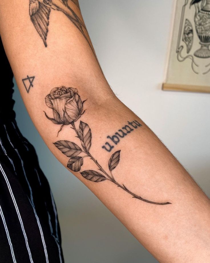 a woman's arm with a rose tattoo on it and the words tattooed in cursive writing