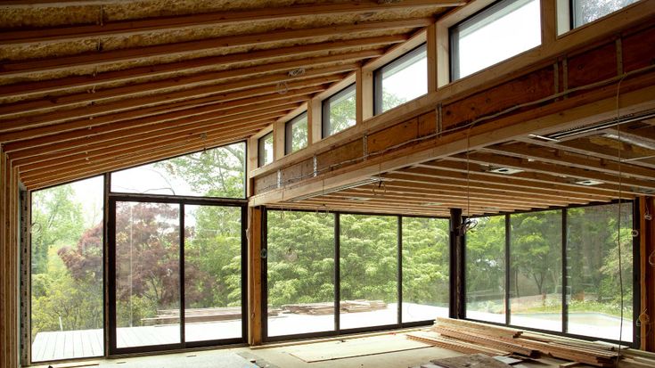 an empty room with lots of windows and wood framing