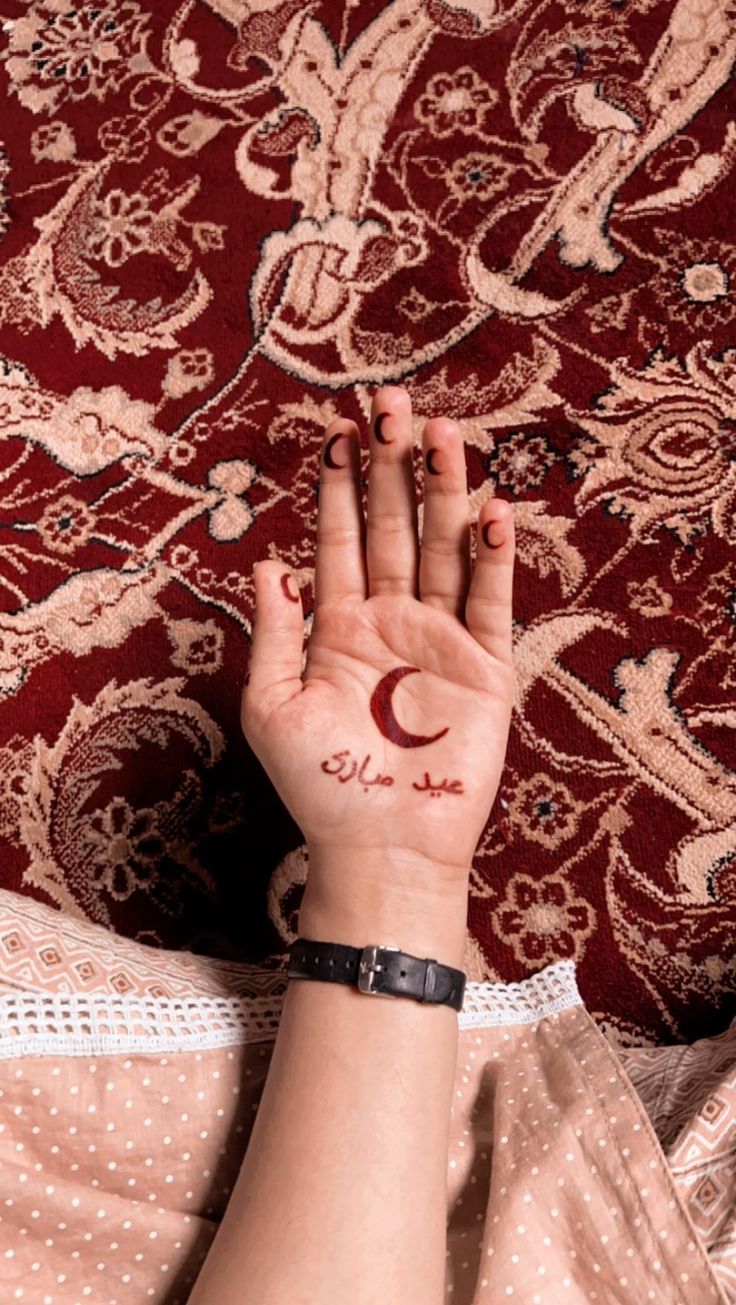 a woman's hand with a crescent tattoo on her left wrist and the word love written in arabic