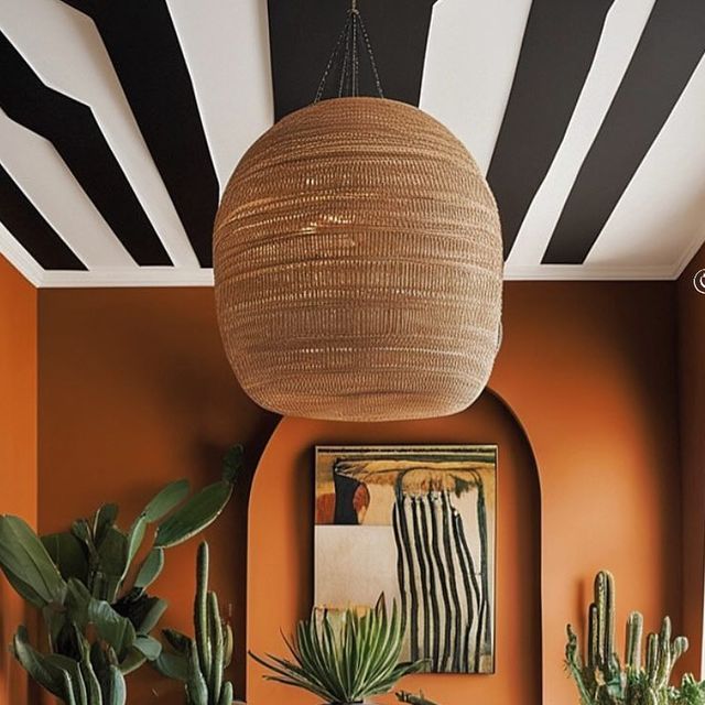 a living room filled with lots of plants next to a painting on the wall and ceiling