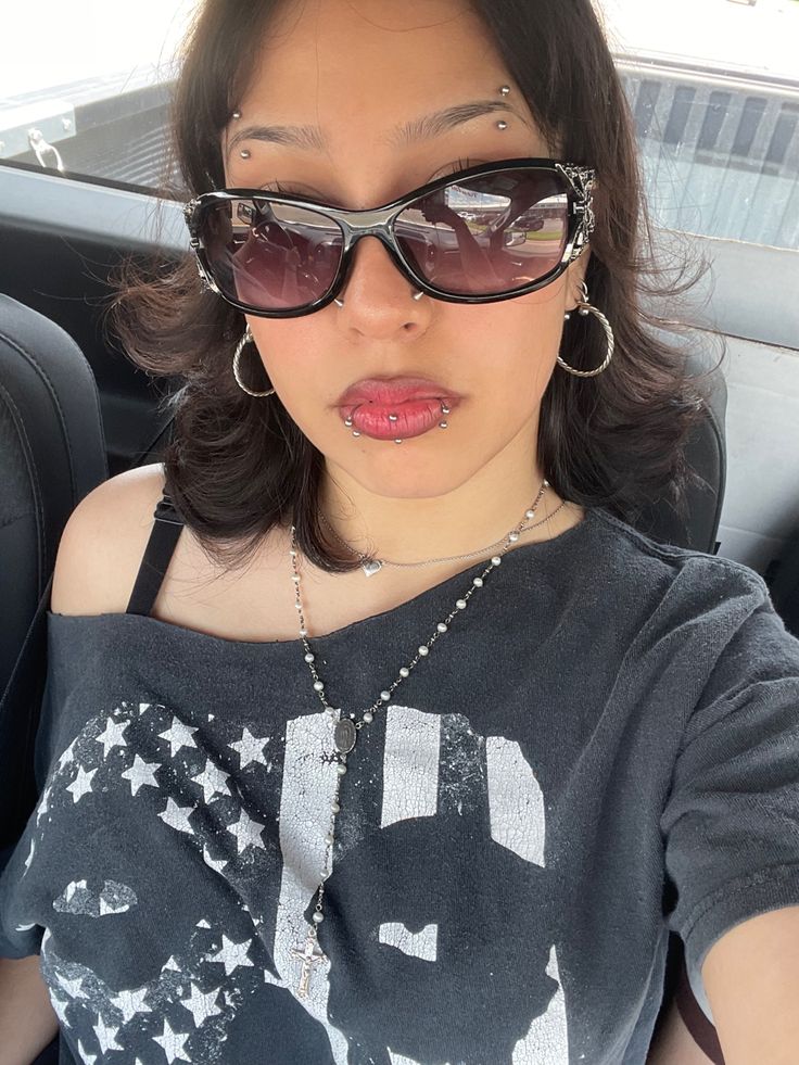 a woman in sunglasses sticking her tongue out while sitting in the back seat of a car